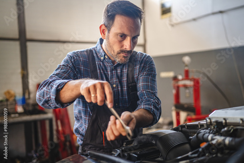 Focused car mechanic work on car engine in automotive workshop