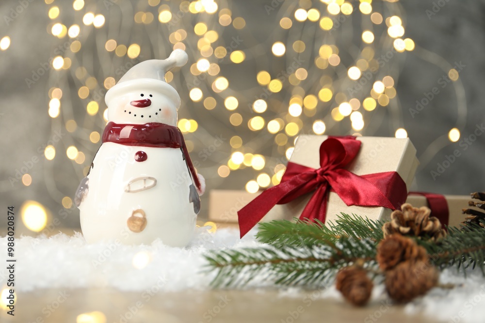 Funny snowman figure and other decor on table against blurred lights Funny snowman figure and other decor on table against blurred lights