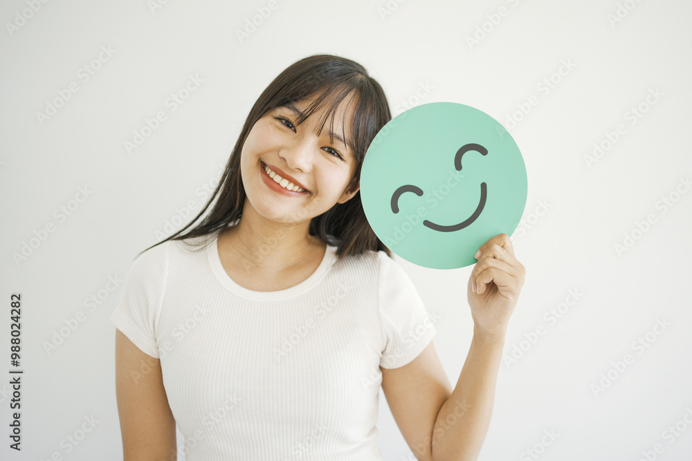 Happy young Asian woman holding smile emoji face, positive mental health, world mental health day concept
Happy young Asian woman holding smile emoji face, positive mental health, world mental health day concept