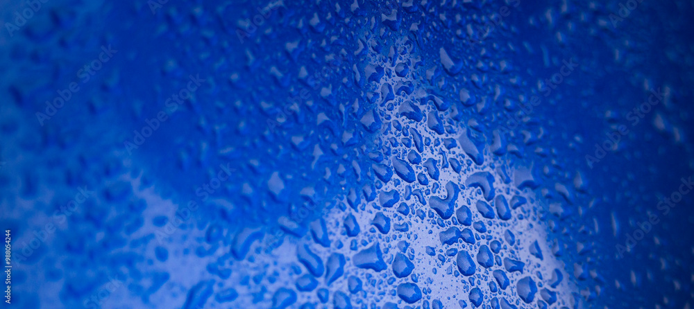 Obraz premium Close up of water drops on blue glass.