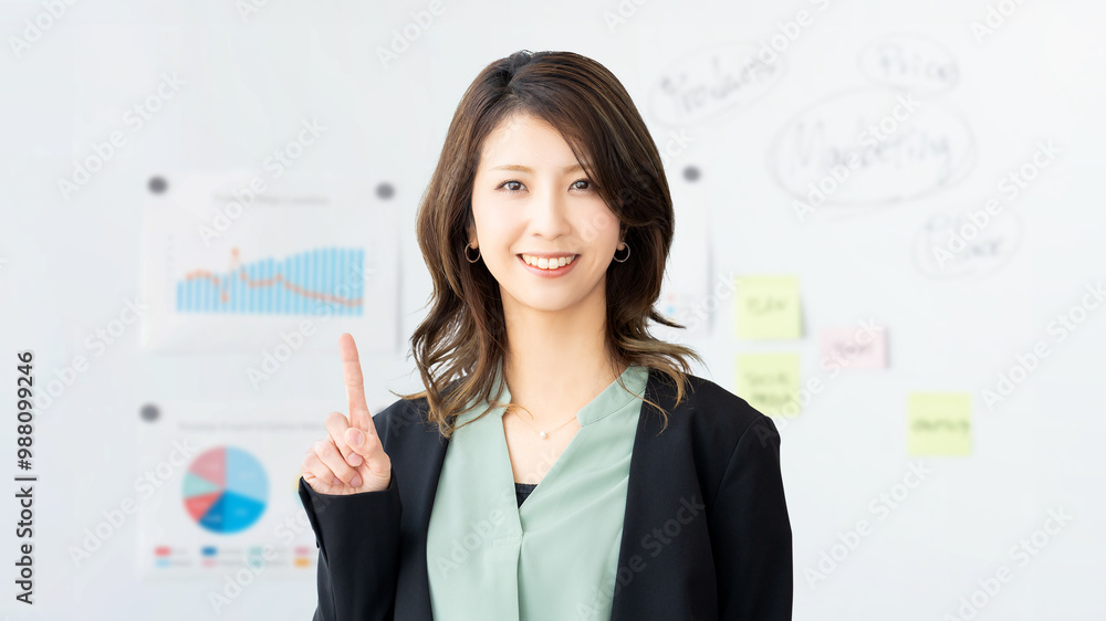 人差し指を立てて案内する笑顔のビジネスウーマン 人差し指を立てて案内する笑顔のビジネスウーマン