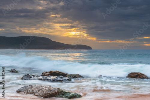 Sunrise at the seaside with rocks and beautiful diffused light by the rain clouds