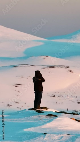 AERIAL: Photographer taking pictures of snowy fells, winter sunrise in Lapland photo