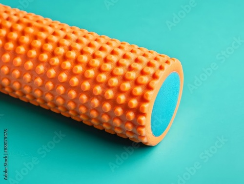 Textured orange foam roller on a teal background. photo