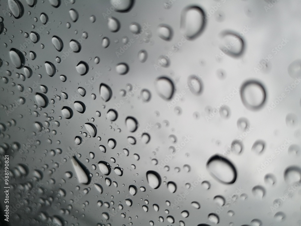Raindrops, water droplets settle on the glass. There is a blurry image in the background. Raindrops, water droplets settle on the glass. There is a blurry image in the background.