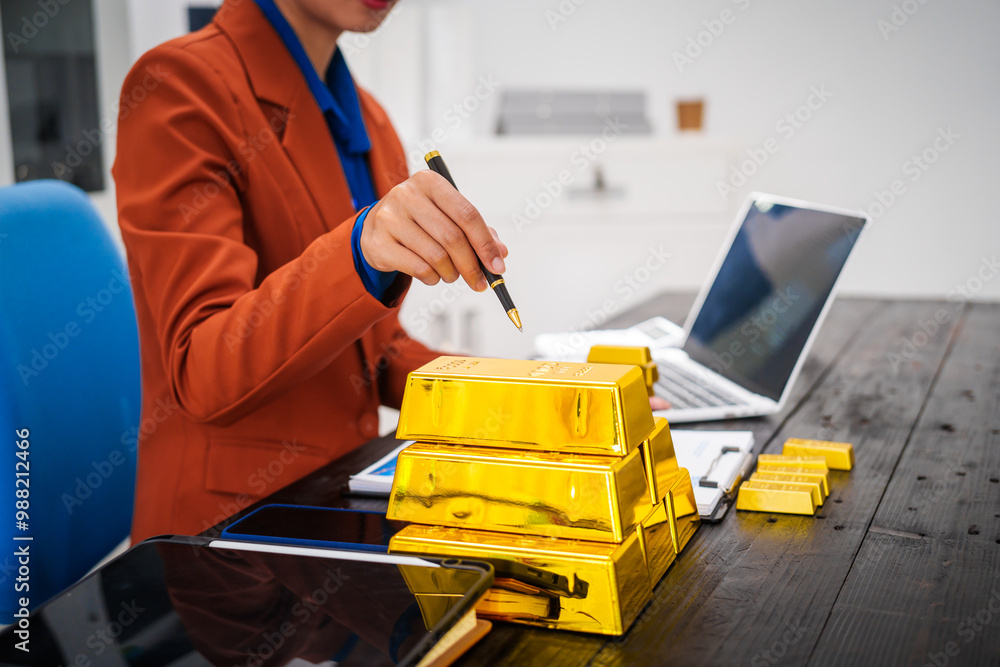 An Asian businesswoman is sitting at her desk in the office,analyzing gold bullion prices,market trends,investment factors,providing in-depth analysis adjust trading strategies for positive returns. An Asian businesswoman is sitting at her desk in the office,analyzing gold bullion prices,market trends,investment factors,providing in-depth analysis adjust trading strategies for positive returns.