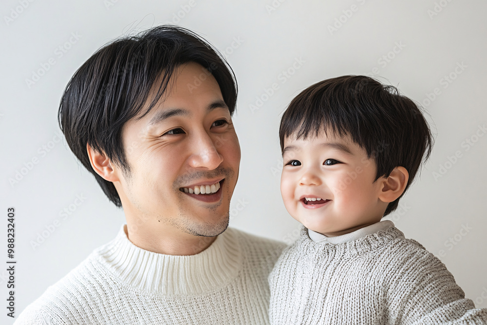 Loving father and young son smiling and sharing joyful moments, either looking at each other or at the camera, in a cozy white studio setting, capturing heartwarming family interactions. Loving father and young son smiling and sharing joyful moments, either looking at each other or at the camera, in a cozy white studio setting, capturing heartwarming family interactions.