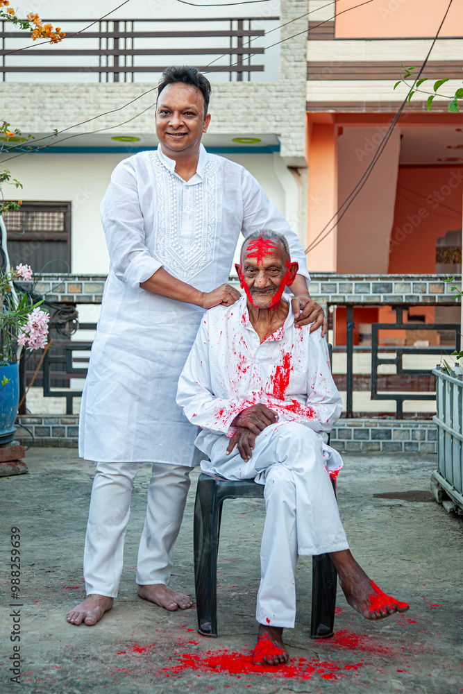 An Indian father and son joyfully celebrate the traditional festival of colors, Holi, symbolizing love and tradition. An Indian father and son joyfully celebrate the traditional festival of colors, Holi, symbolizing love and tradition.