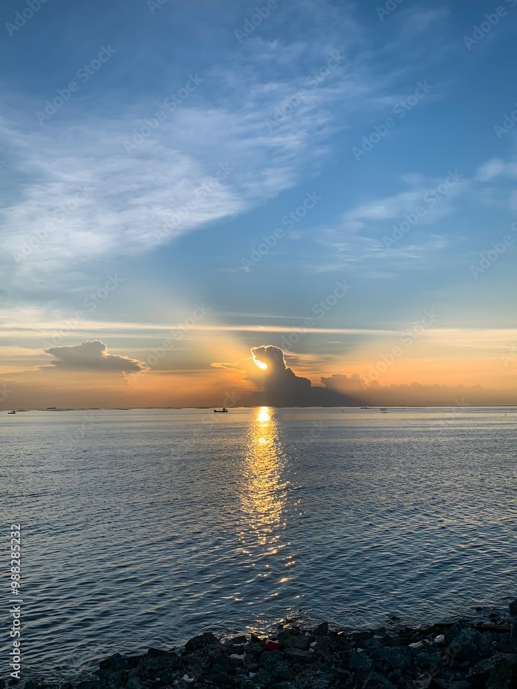 Obraz premium Sunrise Over Calm Sea with Dramatic Sky and Cloud Reflection.