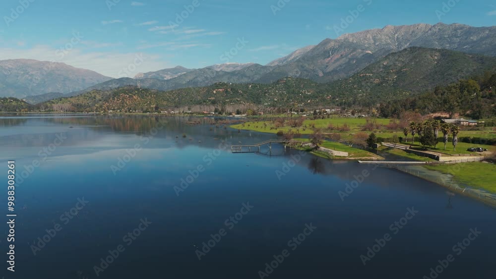 Aerial view of Aculeo Lagoon in Chile, showcasing tranquil waters, lush landscapes, and majestic mountains under a clear blue sky. Aerial view of Aculeo Lagoon in Chile, showcasing tranquil waters, lush landscapes, and majestic mountains under a clear blue sky.