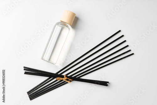 A minimalist display of essential oil and black diffuser sticks on a clean white background