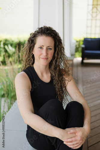 Lifestyle portrait of smiling woman with curly hair outside of home photo