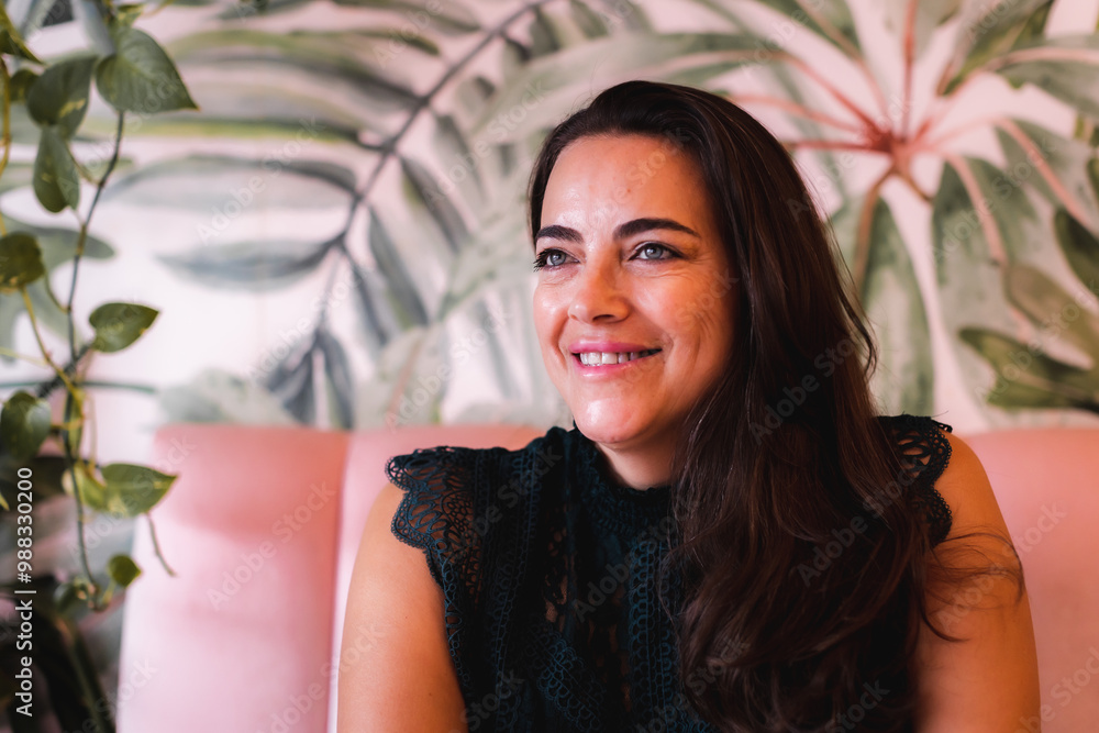 Smiling woman in her 40s sitting on a pink couch Smiling woman in her 40s sitting on a pink couch