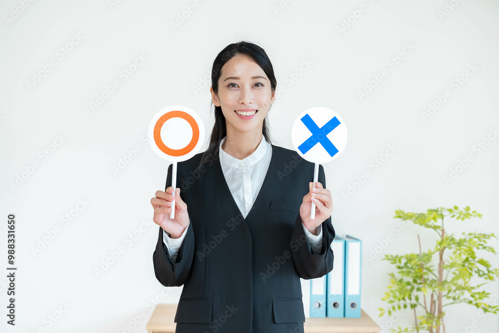 まるばつの札を持つスーツを着た女性