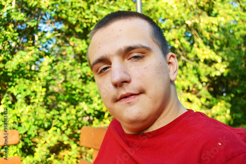 Foto An autistic adult guy looks directly into the camera on a walk