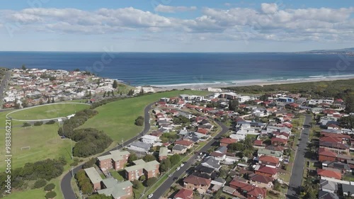 Drone dolly above suburban homes and apartment condos along side of grassy green space overlooking ocean in Port Kembla NSW Australia photo