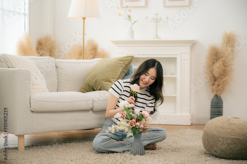 A young girl is arranging flowers in a vase in her living room.