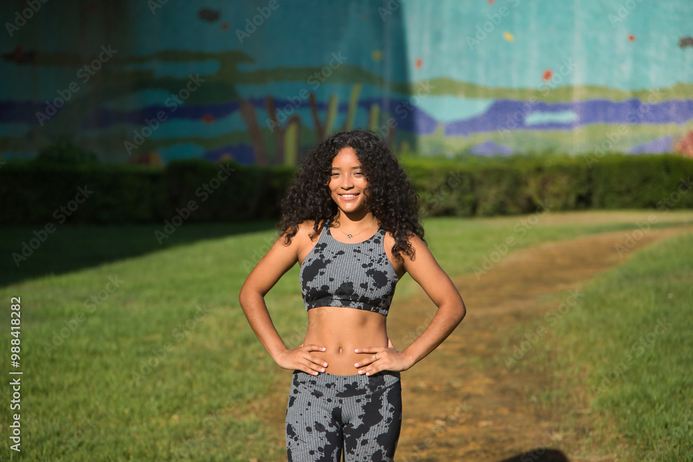 Obraz premium Latina woman, young, beautiful, brunette, with curly hair and sport clothes, with her hands on her waist, happy and content after having completed her exercise routine. Concept sport, exercise.