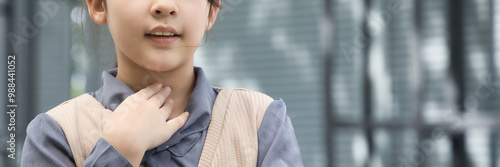 Fotografia Young asian primary schooler girl having sore throat, concept image for health c
