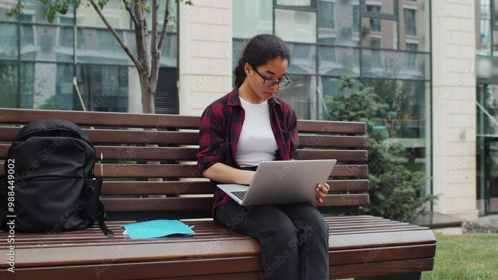 Young woman sitting on bench using laptop Young woman sitting on bench using laptop