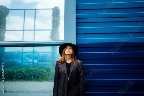 Woman with eyes closed standing in front of blue wall photo