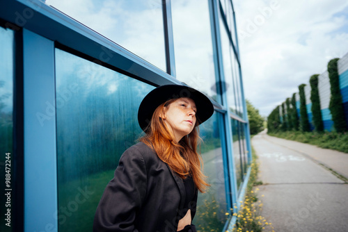 Redhead woman standing near glass wall in street