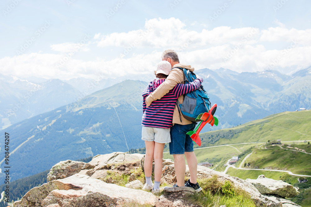 Father and daughter standing with arms around at mountain