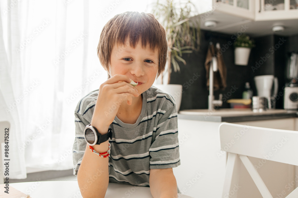 Cute boy eating slice of apple in kitchen Cute boy eating slice of apple in kitchen