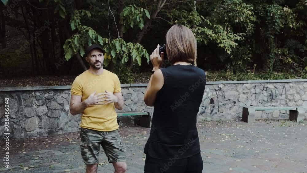 A man and a woman chat and learn how to take photos using a DSLR camera in a park A man and a woman chat and learn how to take photos using a DSLR camera in a park