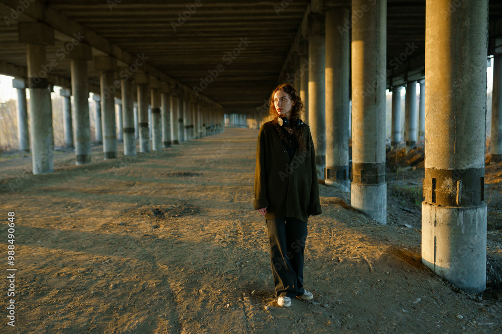 Young woman standing near architectural column under bridge Young woman standing near architectural column under bridge