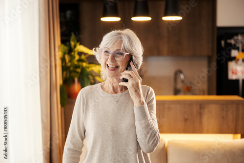 Happy senior woman having phone conversation at home with loved ones.