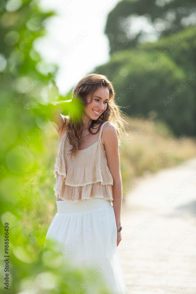 Happy woman with hand in hair standing at footpath Happy woman with hand in hair standing at footpath