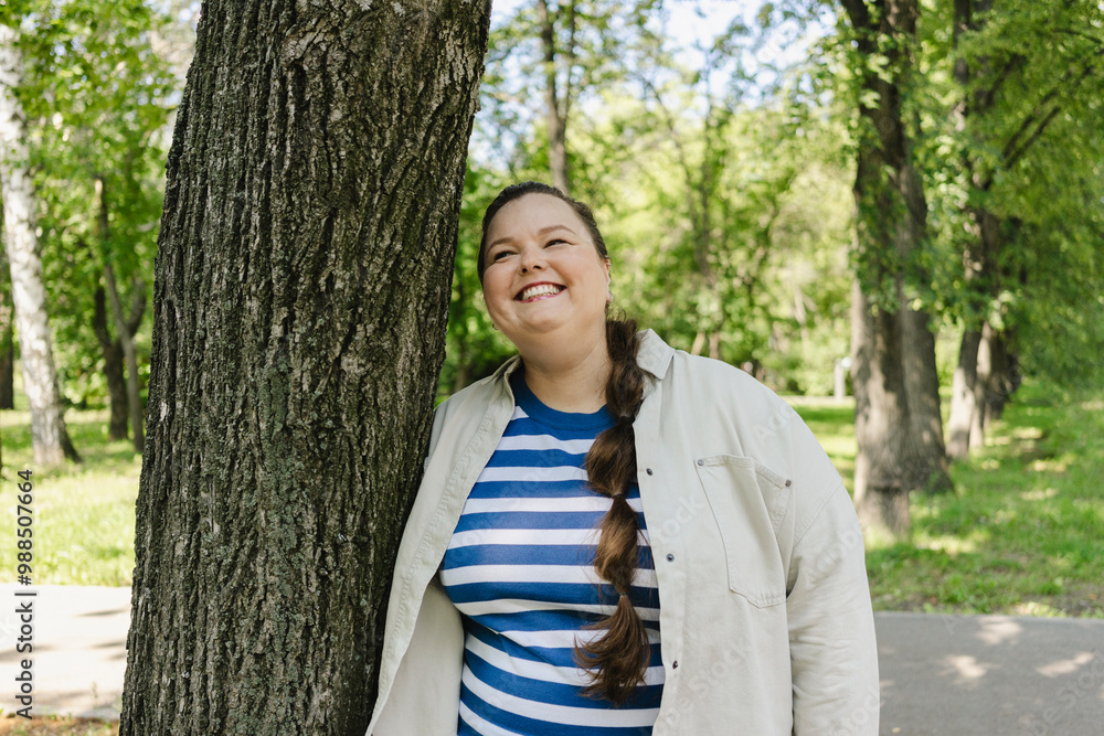 Cheerful woman leaning on tree at public park Cheerful woman leaning on tree at public park