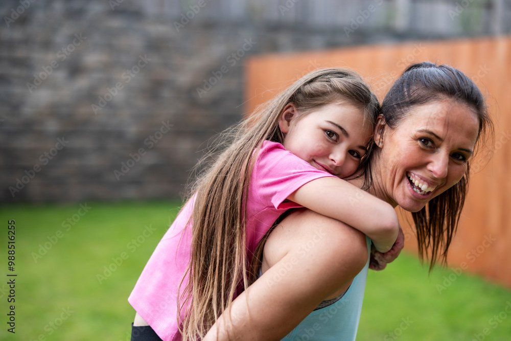Happy woman piggybacking daughter in back yard Happy woman piggybacking daughter in back yard