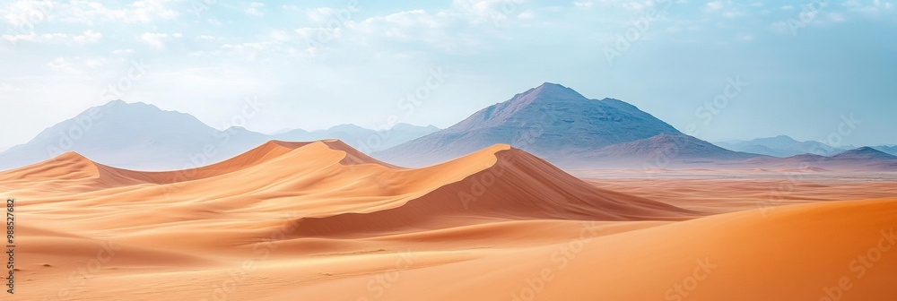 Naklejka premium Endless Dunes Underneath a Soft Sky, sweeping sand dunes stretch towards softly blurred mountains in a vast desert expanse