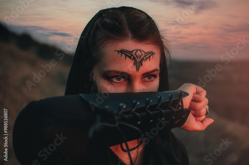 Beautiful girl in black gothic style clothes with tattoo on her face