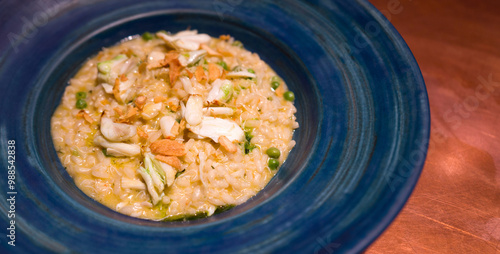 Risotto al granchio e piselli. Italian food. Blue swimmer crab cooked with Carnaroli rice and fresh peas, topped with chili oil and crispy fried garlic for a rich aroma and flavor.