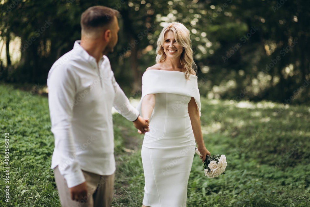 Bride in Elegant White Dress Holding Bouquet Walking in Lush Green Forest with Partner Outdoors Bride in Elegant White Dress Holding Bouquet Walking in Lush Green Forest with Partner Outdoors