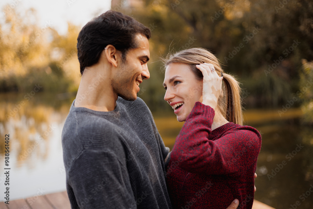Smiling romantic couple looking at each other on pier near lake in autumn Smiling romantic couple looking at each other on pier near lake in autumn