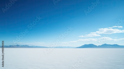 The infinite white expanse of Salar de Uyuni, dotted with distant mountains and under a brilliant blue sky, with no visible horizon.