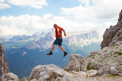 Young happy man high jumping on rocks in the Dolomite mountains.