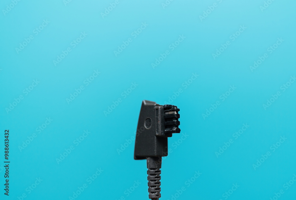 A German standard phone plug displayed against a blue cyan background, showcasing common telecommunications hardware A German standard phone plug displayed against a blue cyan background, showcasing common telecommunications hardware