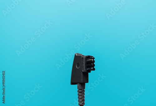 A German standard phone plug displayed against a blue cyan background, showcasing common telecommunications hardware photo