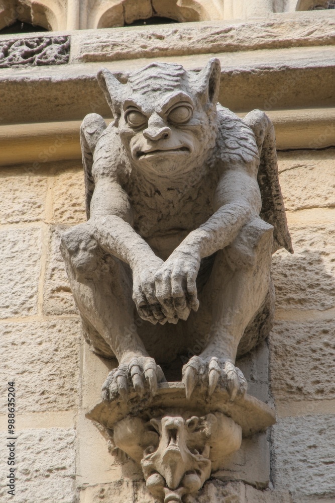 An ornate gothic gargoyle with winged details on the facade of a stunning ancient architecture An ornate gothic gargoyle with winged details on the facade of a stunning ancient architecture