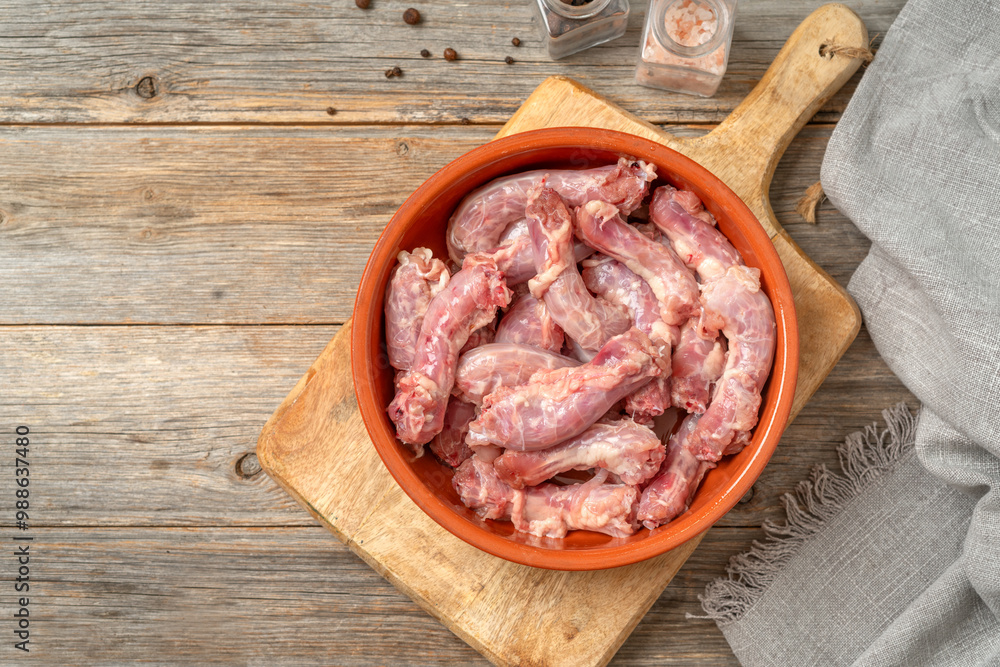 Raw chicken necks in a bowl on a gray wooden culinary background. Top view with a copyspace