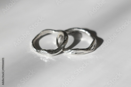 Two beautifully crafted organic shaped silver rings with textured surface on white background.