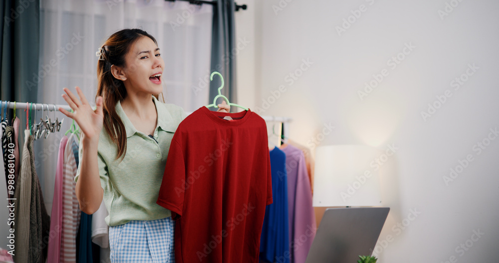 Selective focus, Cheerful female influencer checking orders on laptop while live selling clothes in home studio. Remote buying, Online shopping, Sell products online Selective focus, Cheerful female influencer checking orders on laptop while live selling clothes in home studio. Remote buying, Online shopping, Sell products online