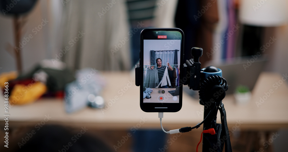 Obraz premium Selective focus on mobile phone of Cheerful woman influencer is live streaming sell clothes on social media or blogging in home studio. Remote buying, Online shopping, Sell ​​products online