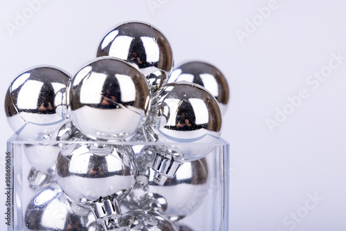 Decorative glass vase containing silver holiday balls in varying sizes, used as festive Christmas ornaments photo