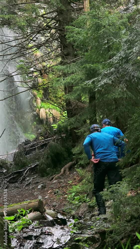 Wilderness Explorers Approaching a Breathtaking Waterfall in a Secluded Forest Wilderness Explorers Approaching a Breathtaking Waterfall in a Secluded Forest